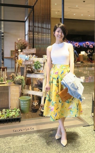 明亮的黃色花圓裙用白色削肩上衣和牛仔外套來中和